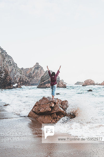 Junge Frau steht auf einem Felsen am Praia da Ursa  Lissabon  Portugal
