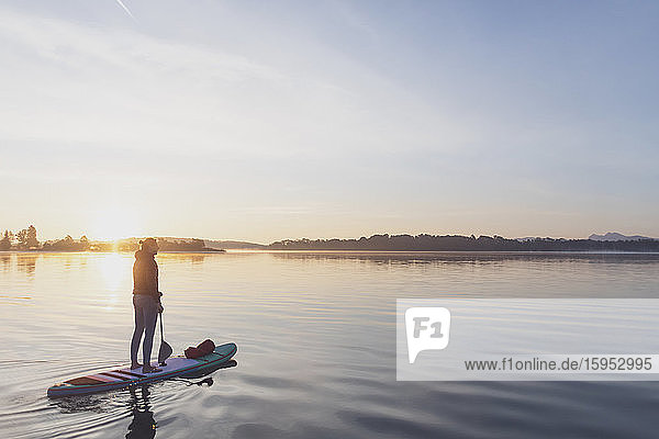 Woman standing on sup board in the morning on a lake  Germany