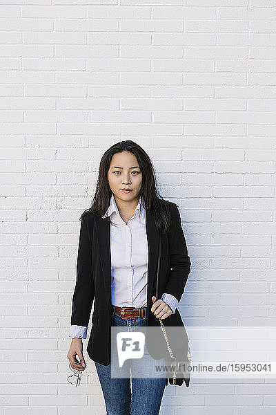 Portrait of young businesswoman standing in front of white wall