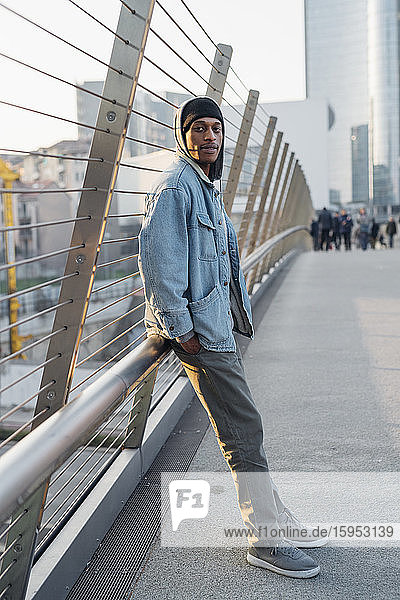 Portrait of young man standing on a bridge in the city at sunset  Milan  Italy