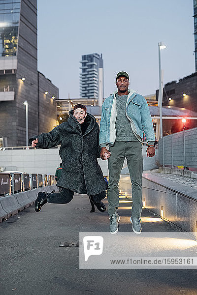 Glückliches junges Paar springt in der Stadt in der Abenddämmerung  Mailand  Italien