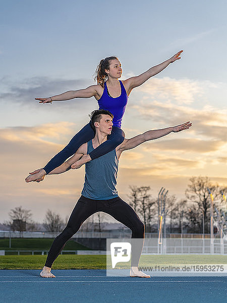 Young couple doing acrobatics at sunset