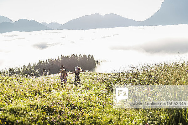 Zwei Freundinnen laufen auf einer Wiese in den Bergen  Achenkirch  Österreich