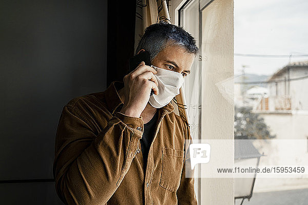 Man wearing protective mask and looking out of the window