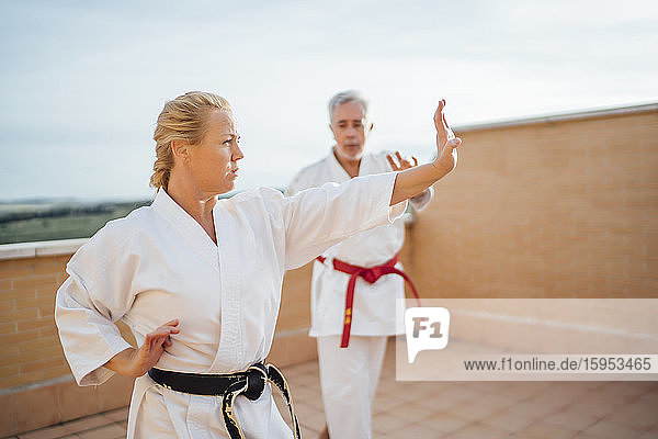 Frau mit Lehrer beim Karatetraining auf der Terrasse