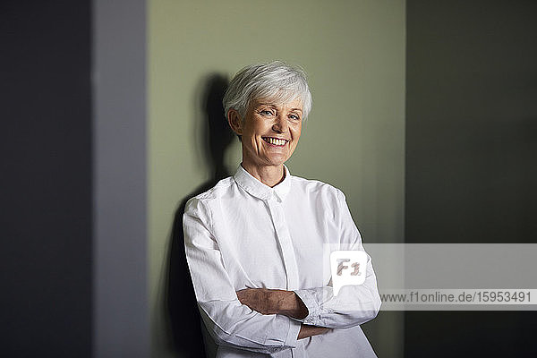 Porträt einer autofreien älteren Geschäftsfrau  die an der Wand lehnt
