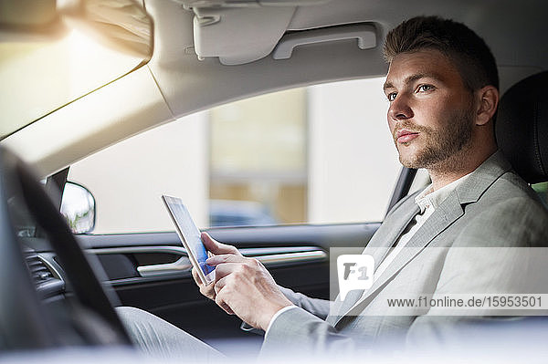 Young businessman using tablet in a car