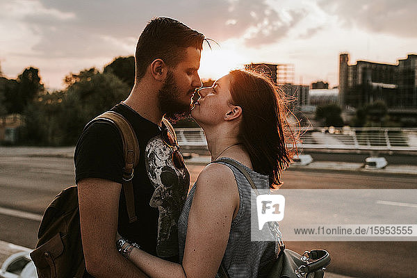 Liebevolles junges Paar umarmt sich bei Sonnenuntergang an einer Straße  Berlin  Deutschland