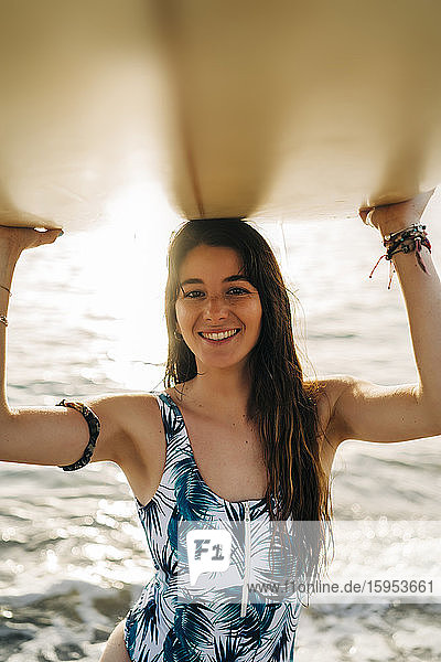 Porträt einer glücklichen jungen Frau mit Surfbrett am Strand  Almeria  Spanien