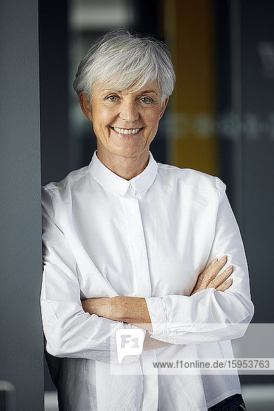 Porträt einer lächelnden älteren Geschäftsfrau mit verschränkten Armen