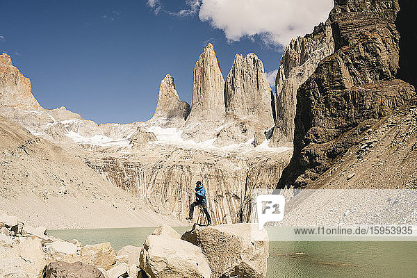 Wanderer springt in der Berglandschaft am Seeufer am Mirador Las Torres im Nationalpark Torres del Paine  Patagonien  Chile