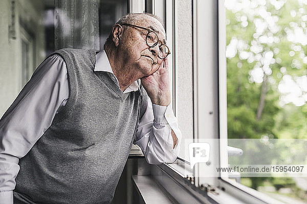 Portrait of sad senior man looking out of window