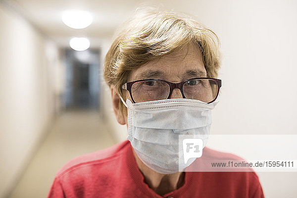 Senior woman with protective mask in corridor of retirement home