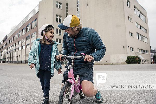 Happy father with daughter on her bicycle