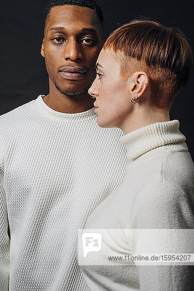 Studioporträt eines gemischtrassigen Paares mit weißen Pullovern