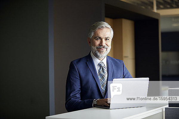 Portrait eines reifen Geschäftsmannes mit Laptop im Büro