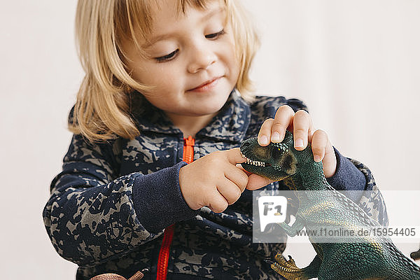Lächelndes kleines Mädchen spielt mit Spielzeug-Dinosaurier