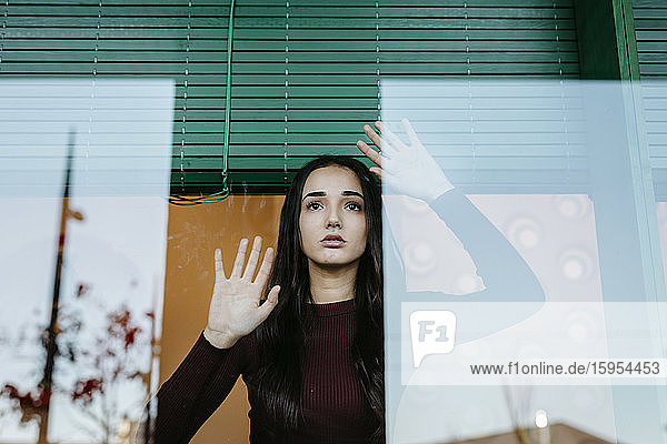 Porträt einer jungen Frau hinter einer Fensterscheibe