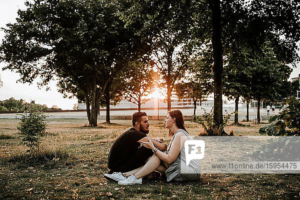 Young couple sitting in a park at sunset