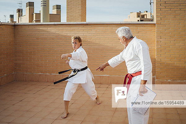 Frau mit Lehrer beim Karatetraining auf der Terrasse
