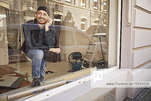 Mann renoviert Ladenlokal  benutzt Kopfhörer am Fenster