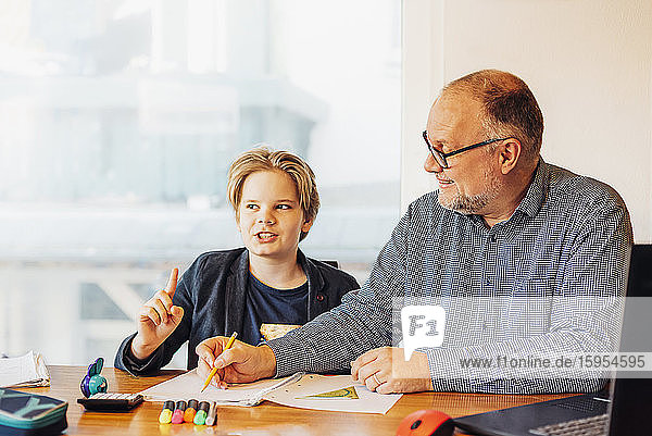 Vater hilft Sohn bei den Hausaufgaben am Schreibtisch