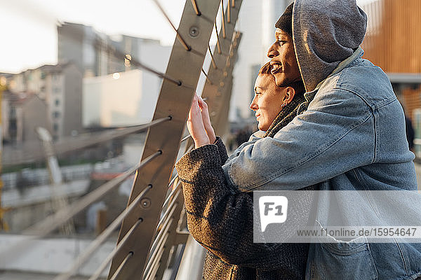 Affectionate young couple on a footbridge at sunset