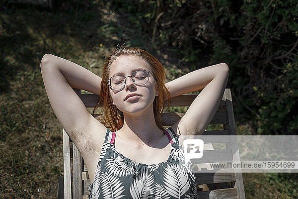 Porträt einer jungen Frau beim Sonnenbaden auf einem Liegestuhl im Garten