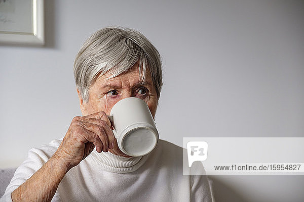 Porträt einer älteren Frau  die zu Hause Tee trinkt