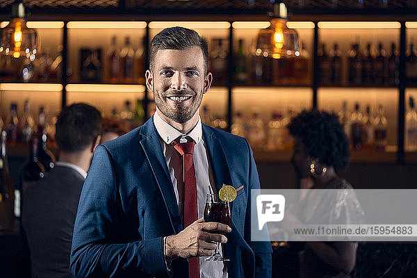 Porträt eines glücklichen jungen Mannes bei einem Cocktail in einer Bar