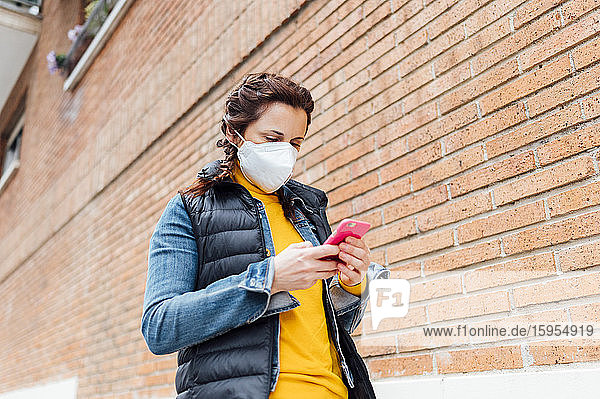Woman covering her face with protective mask and using smartphone