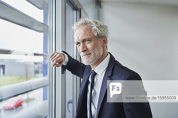 Portrait of confident businessman looking out of window