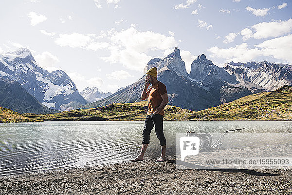 Man on the phone in mountainscape at lakeside in Torres del Paine National Park  Patagonia  Chile
