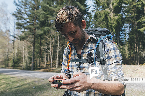 Junger Mann überprüft Navigationsgerät im Wald