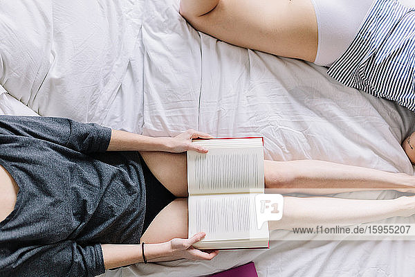 Ernten von zwei Frauen in Unterwäsche  die mit einem Buch auf dem Bett liegen