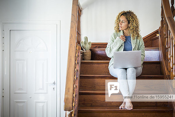 Frau sitzt auf einer Treppe und benutzt einen Laptop