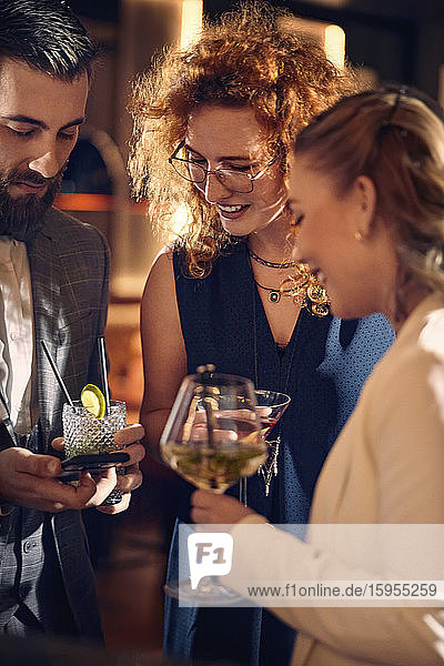 Freunde bei Cocktails und Smartphone-Gesprächen in einer Bar