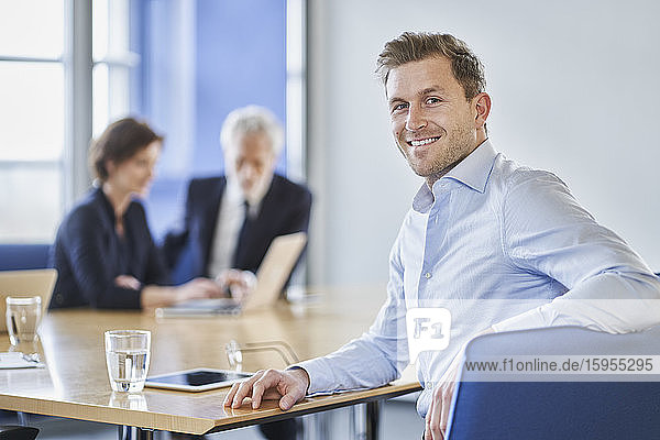 Porträt eines lächelnden Geschäftsmannes während einer Sitzung im Amt