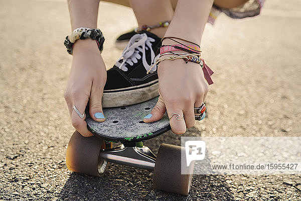 Hände einer jungen Frau  die ein Skateboard hält  Nahaufnahme