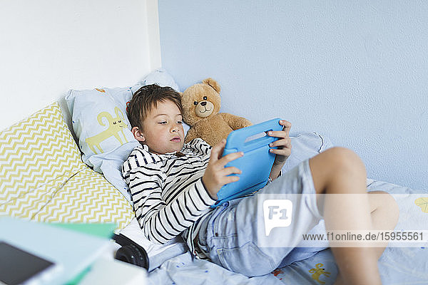 Boy lying in bed using digital tablet