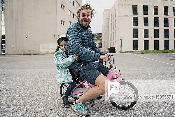 Playful father with daughter on her bicycle