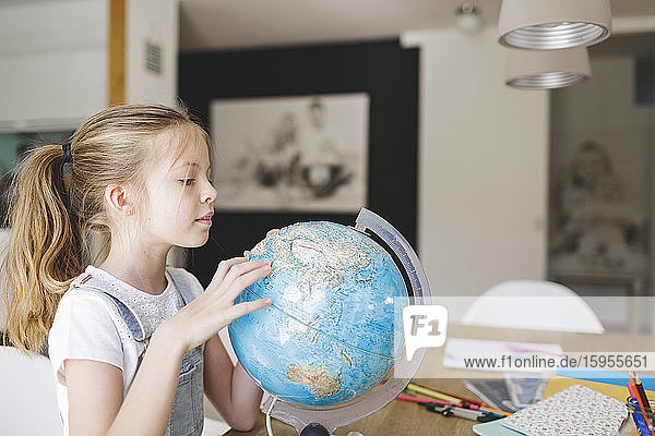 Mädchen schaut zu Hause auf den Globus
