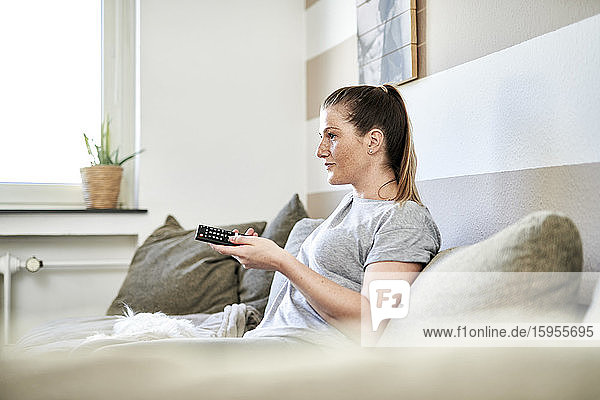 Frau sieht fern  während sie zu Hause auf dem Sofa sitzt