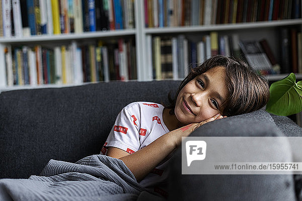 Portrait of smiling boy leaning comfortable sofa in living room at home