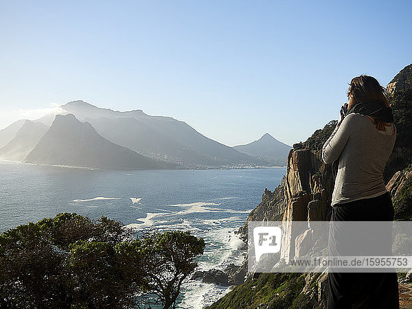 Frau fotografiert eine Berg- und Meereslandschaft  Chapman's Peak Drive  Südafrika