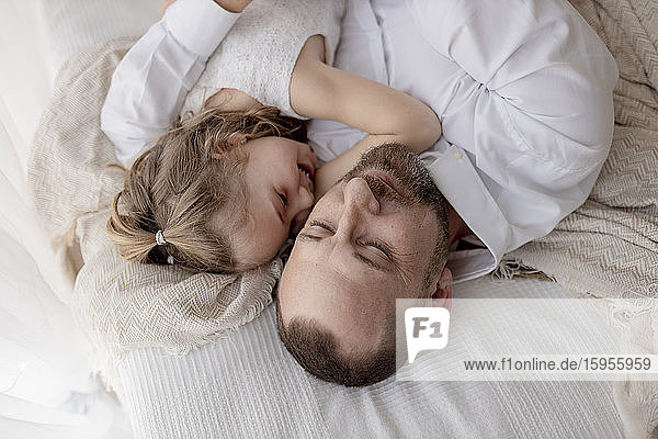 Vater und kleine Tochter ruhen gemeinsam im Bett