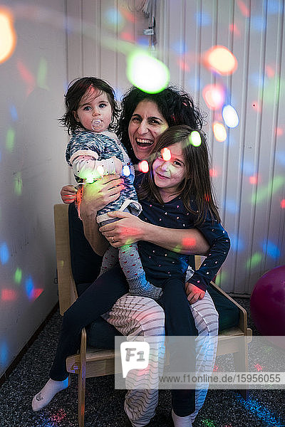 Happy mother with two daughters surrounded by disco lights