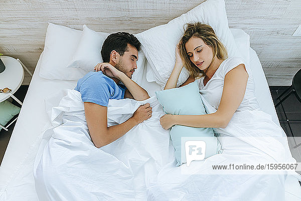 High angle view of couple sleeping on bed in bedroom at home