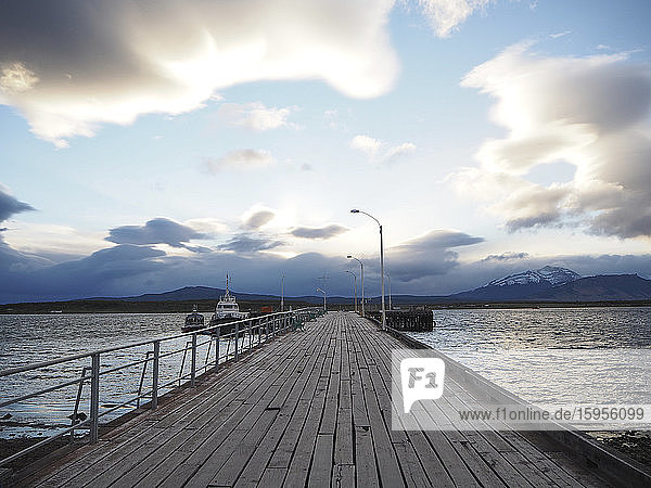 Wooden pier and boats on sea against sky  Puerto Natales  Chile