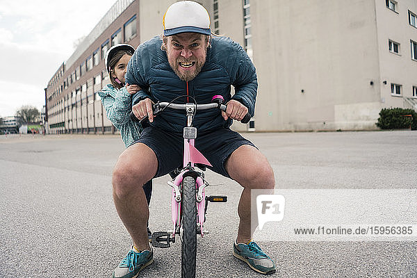 Playful father with daughter on her bicycle